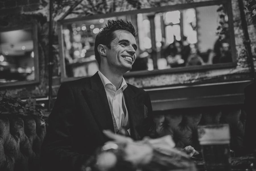 The groom sits at a table and smiles in the King Arms public house