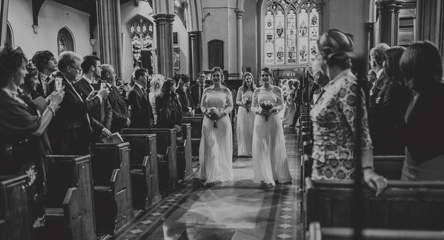 The bridesmaids walk up the aisle of the Church together carrying their bouquets