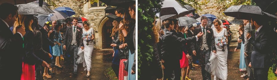 Wedding guests hold umbrellas and throw confetti at the bride and groom outside the Church