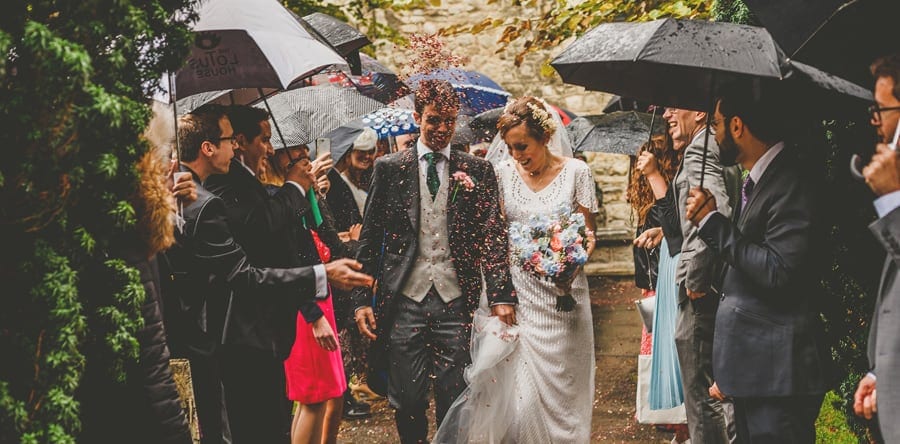 Confetti is thrown in the air as the bride and groom walk out of the Church together