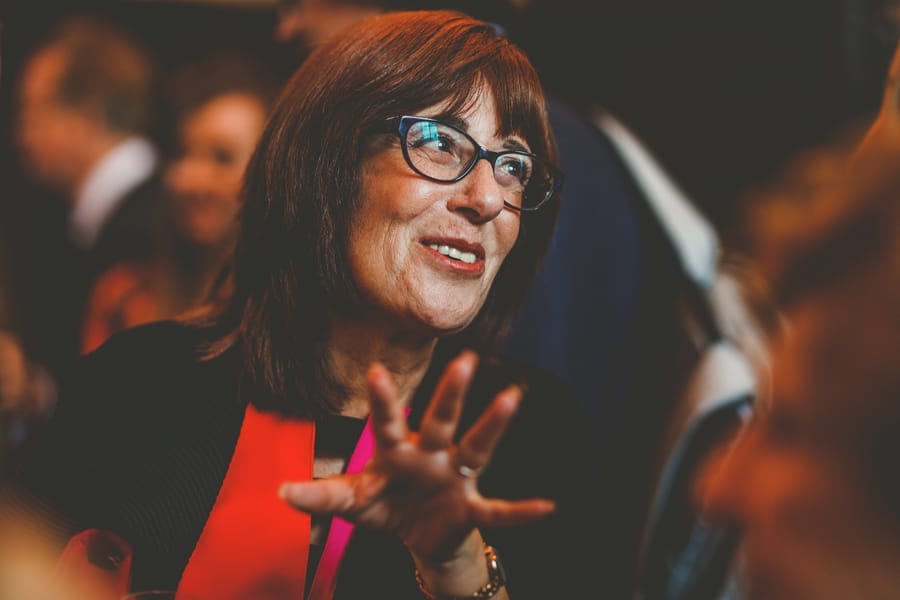 A wedding guest smiles at friends as she stands in a room at Fulham Palace