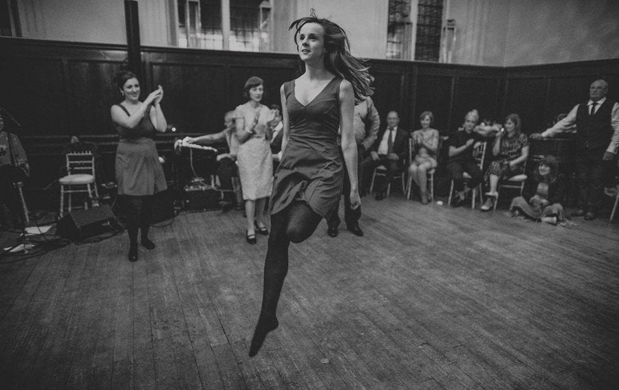 A lady with no shoes on jumps in the air on the dancefloor at Fulham Palace