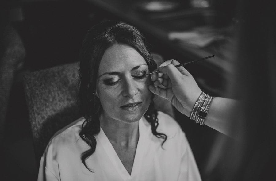 The make up artist applies eye liner to the bride