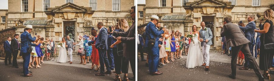 The bride and groom walk out of Goldney Hall wedding venue as friends and family throw confetti