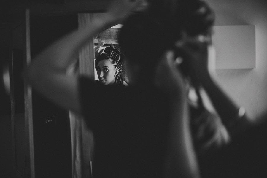 The bride fastens her hair back as she looks at herself in the mirror