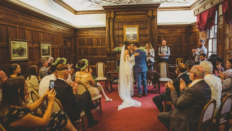 The bride places her left hand onto the grooms shoulder during the wedding ceremony