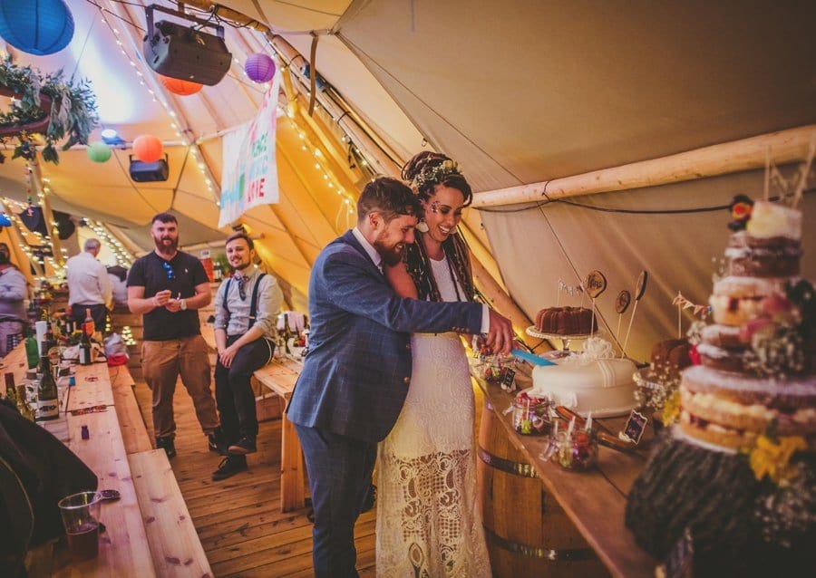 The bride and groom cut the cake in the tipi at Hadsham Farm.