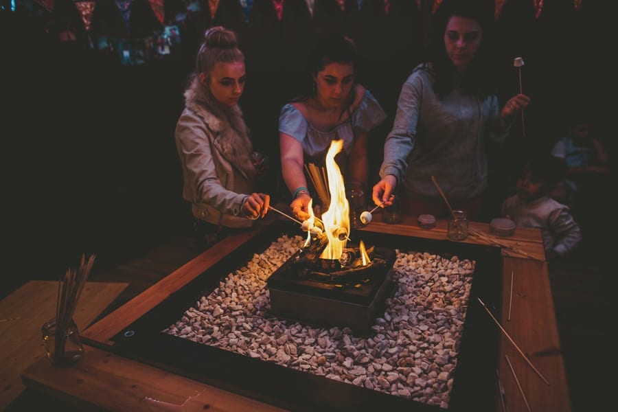 Wedding guests toasting marshmallows in the tipi at Hadsham Farm