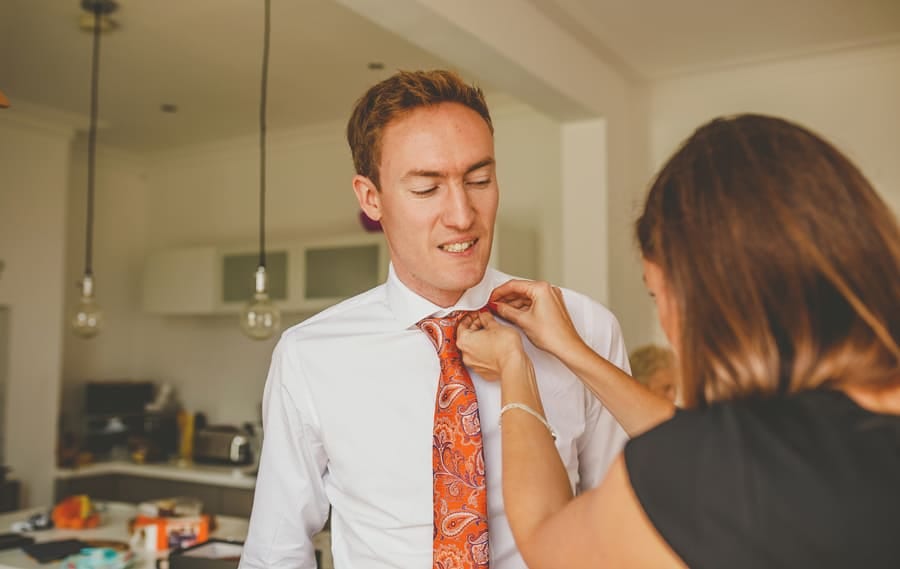 The grooms sister helps the groom with his collar and tie