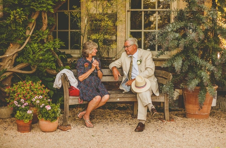 The bride and groom's family sit down on a bench outside the house and talk to each other