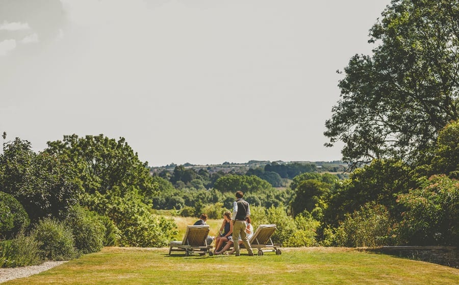 Wedding guests sit on sun loungers in the gardens and talk to each other
