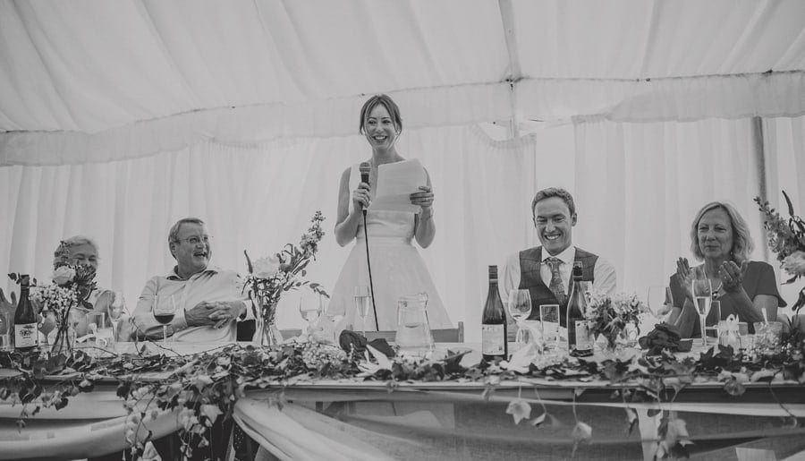 The bride stands up and delivers her speech to the wedding party in the marquee