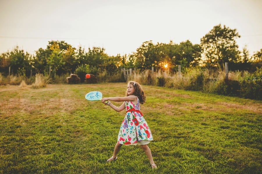 A little girl plays with a rubber bat and softball next to the marquee