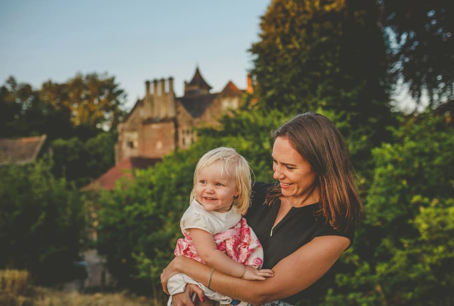 The grooms sister holds her daughter in her arms and smiles outside the marquee