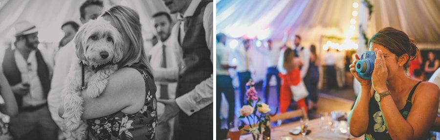A wedding guest holds the bride and grooms dog in her arms and a wedding guest takes a photograph
