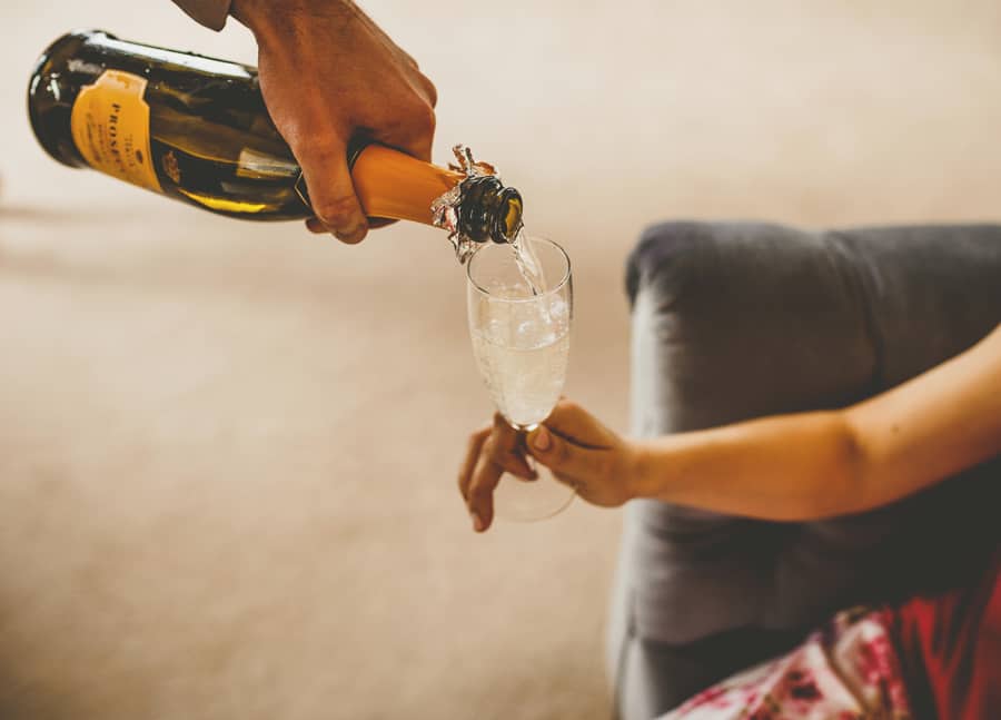 A bridesmaid pours champagne into a flute glass