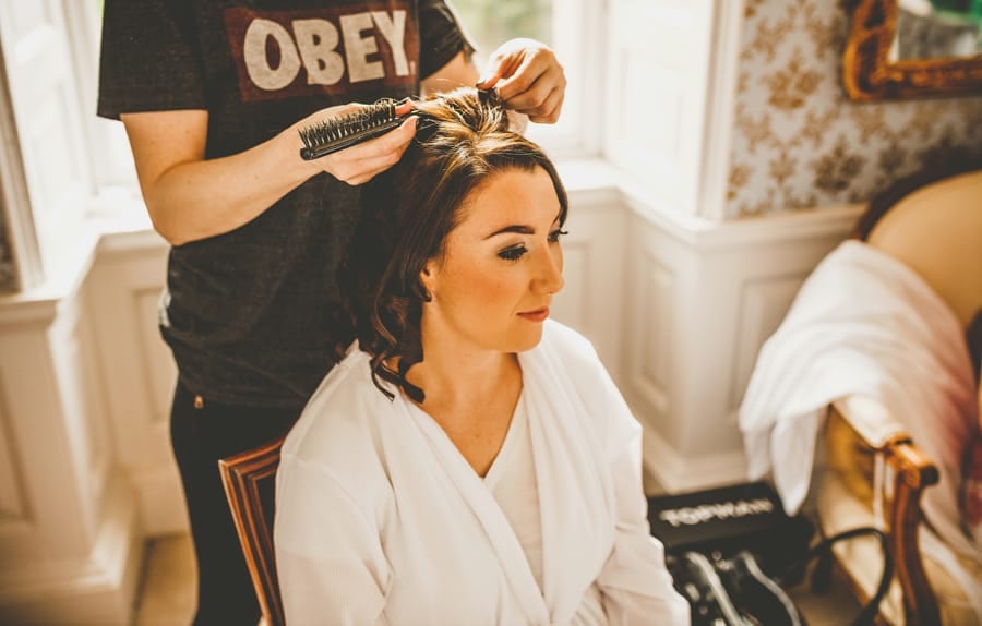 The make up artist curls a bridesmaids hair