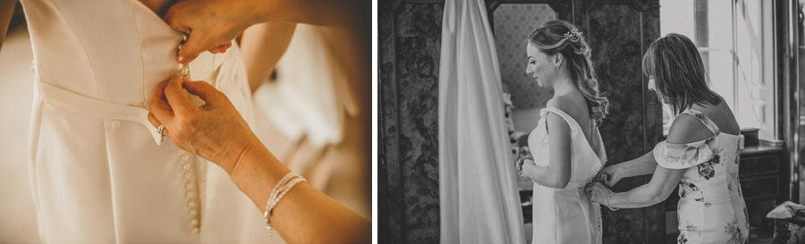 A bridesmaid ties the back buttons of the brides wedding dress
