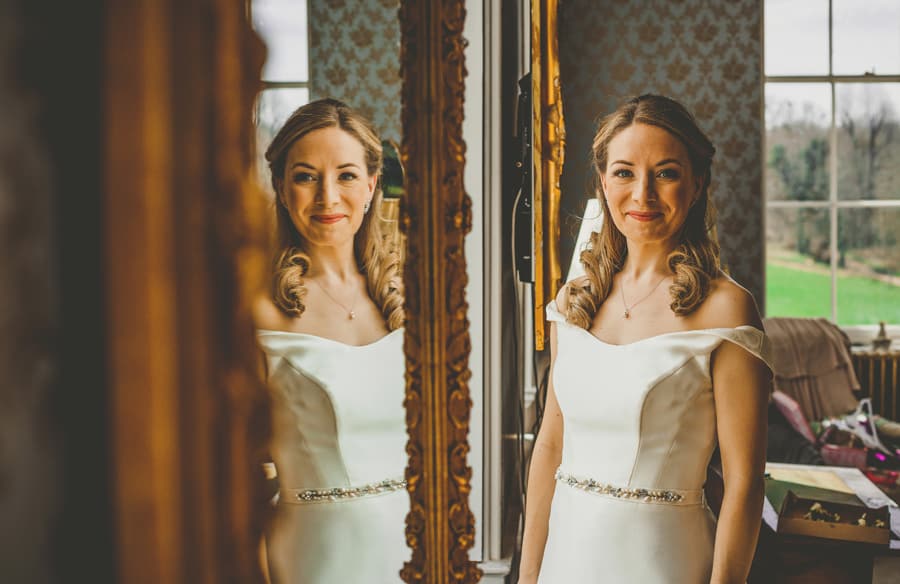 The bride poses for a photograph next to a window in the master bedroom at Kings Weston House in Bristol