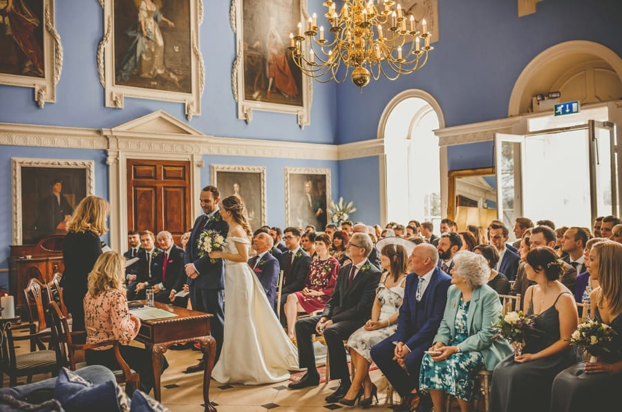 The bride greets the groom as wedding guests sit and watch