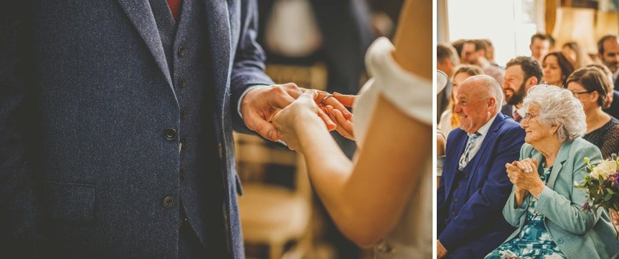 The bride holds the grooms hand as the brides grandmother sits in a chair and watches the wedding ceremony