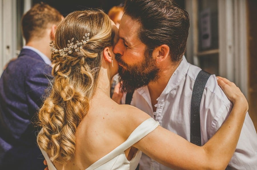 A wedding guest kisses the cheek of the bride outside Kings Weston House