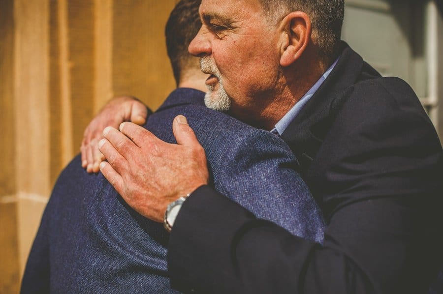 A wedding guest puts his arms around the groom