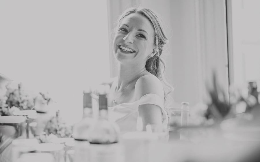 The bride laughs at her father's wedding speech as she sits at a table