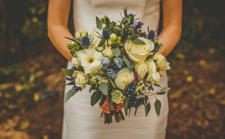 The bride holds her flower bouquet in both hands