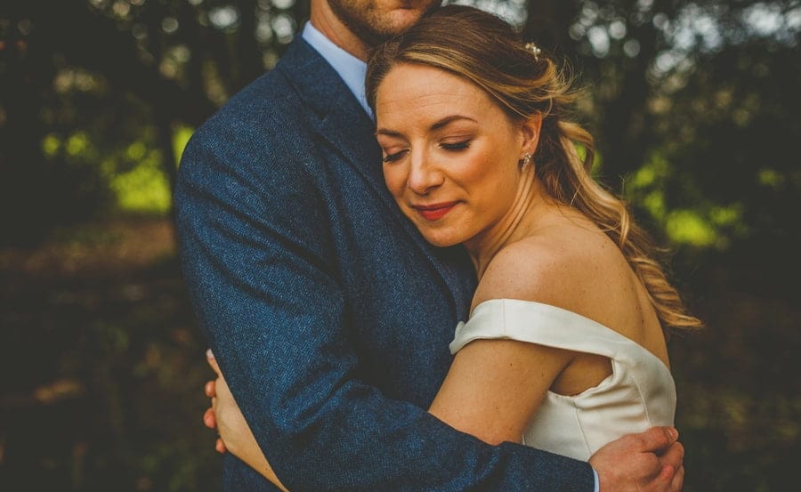 The bride places her arms around the groom and places her head on his chest