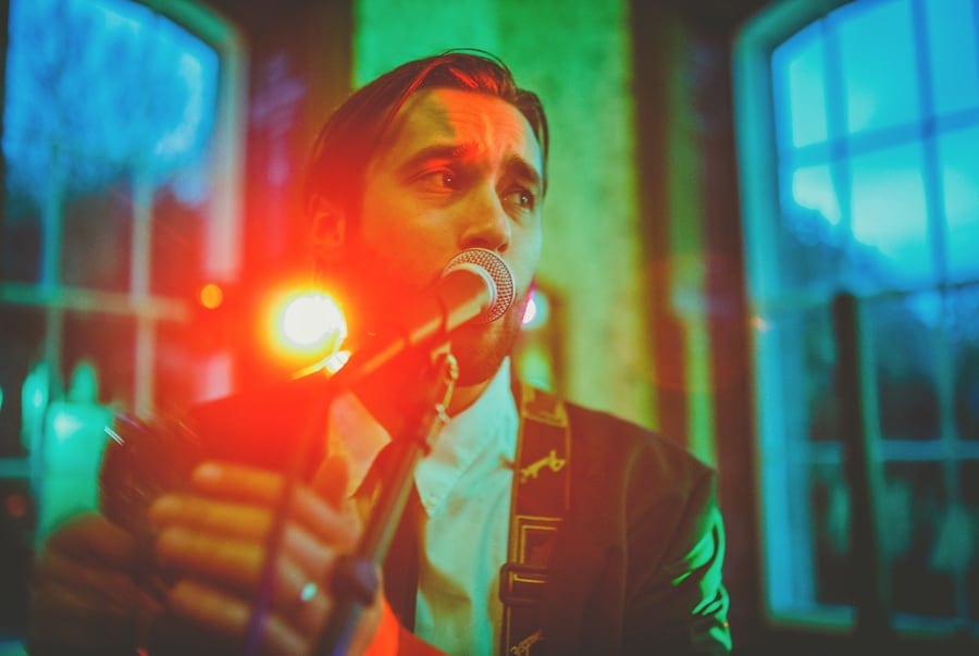 The singer of the wedding band sings into a large microphone and shakes a tambourine