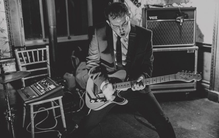 The guitarist of the wedding band plays on his guitar