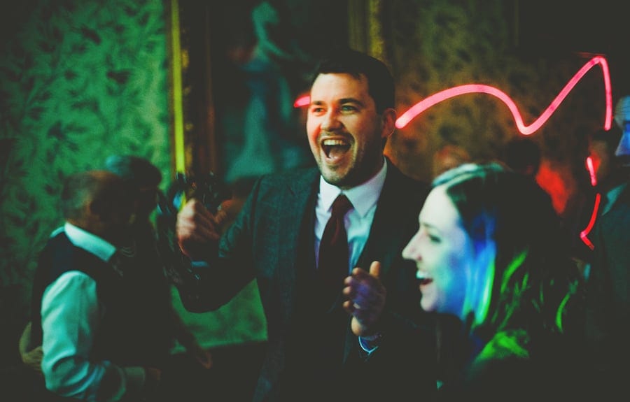 A wedding guest laughs with a friend on the dancefloor
