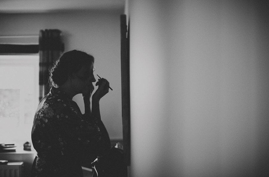 Little Quarme wedding photographer 0006 | somerset-wedding-photographer A bridesmaid puts makeup on as she looks into a large mirror hanging on a wall