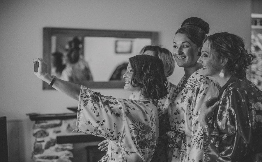 Little Quarme wedding photographer 0013 | somerset-wedding-photographer A bridesmaid holds up a mobile phone and takes a photograph of herself and her friends in the cottage