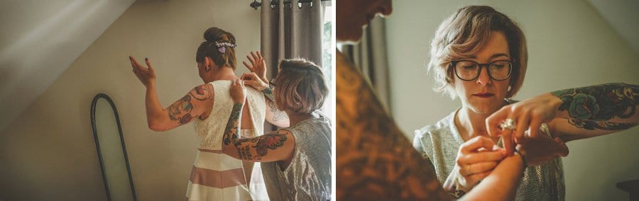 Little Quarme wedding photographer 0015 | somerset-wedding-photographer A bridesmaid helps the bride put on her dress in the bedroom of a cottage