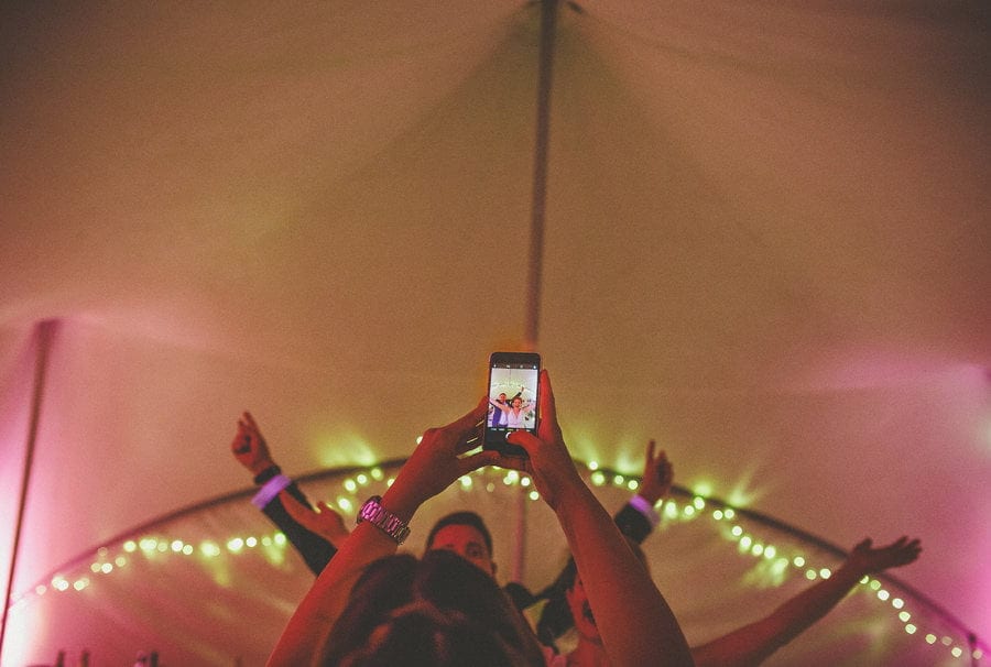 Little Quarme wedding photographer 0058 | somerset-wedding-photographer A wedding guest holds up a mobile phone and takes a photograph of people dancing in the outdoor marquee