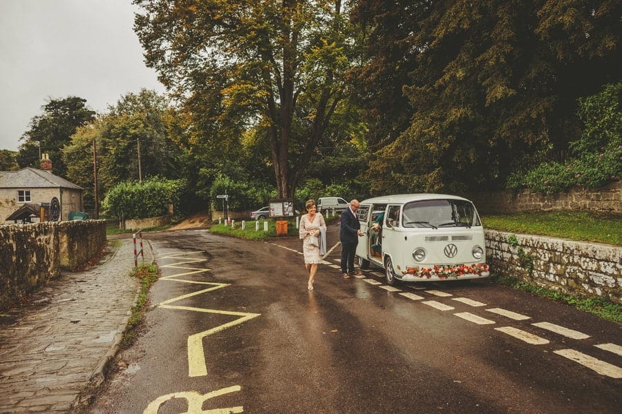 The brides mother walks away from the wedding car towards the Church