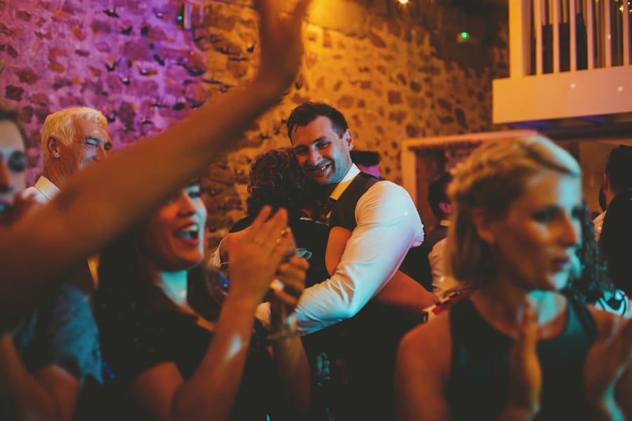 The groom puts his arms around his mother on the dancefloor
