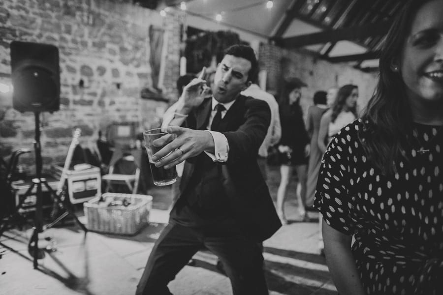 A wedding guest dancing with a drink in his hand