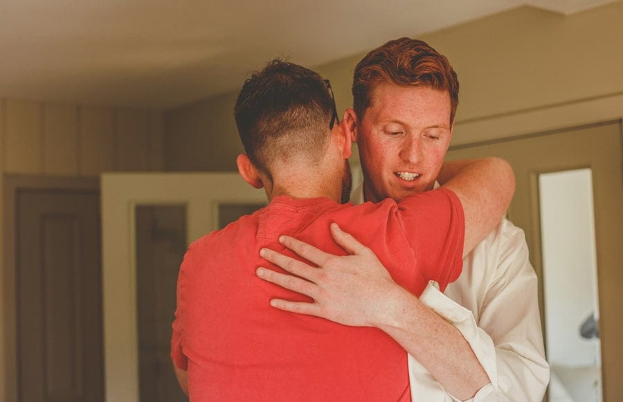 The groom puts his arms around one of the ushers