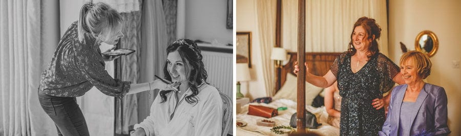 The make up artist applies makeup to the face of the bride who is sat on a chair looking out of a window