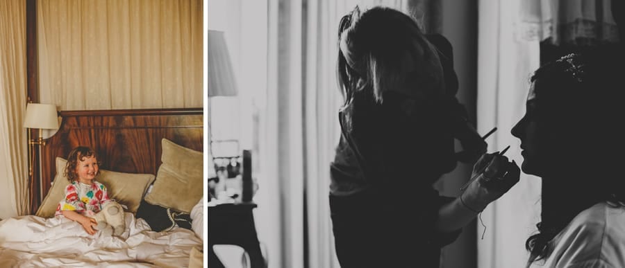 The bride's niece sits in bed and laughs at one of the bridesmaids talking to her