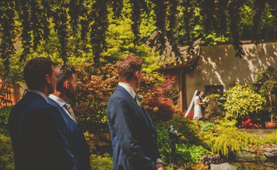 The groom watches the bride arrive for the outdoor ceremony at the Matara Centre