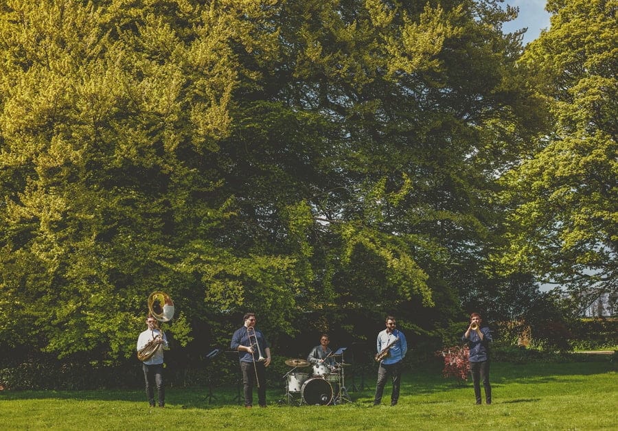The wedding band perform next to a large tree on the lawn at the Matara Centre
