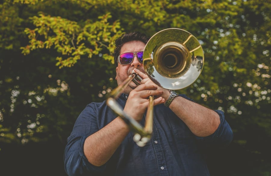 A member of the wedding band plays his instrument outside