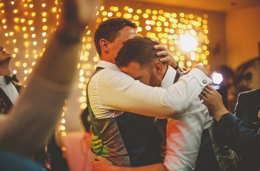 The groom hugs the best man on the dancefloor