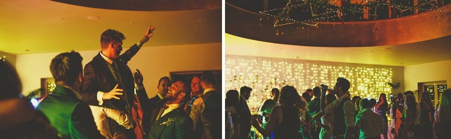 The wedding party lift the groom into the air on the dancefloor