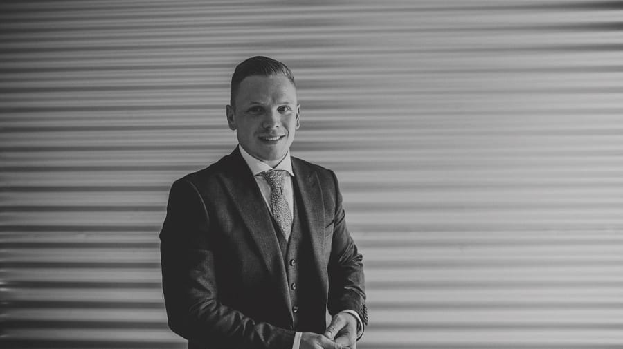 The groom poses for a photograph at Over Barn