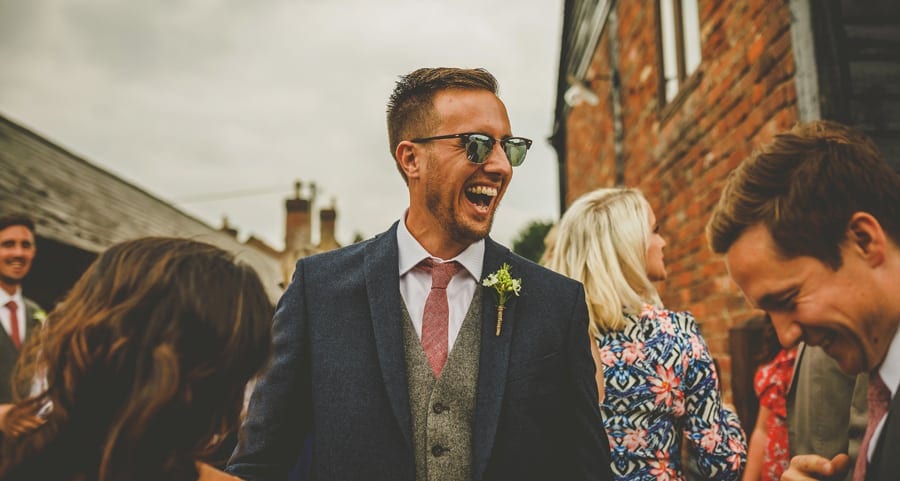 An usher laughs at a joke told by a friend in the courtyard at Over Barn